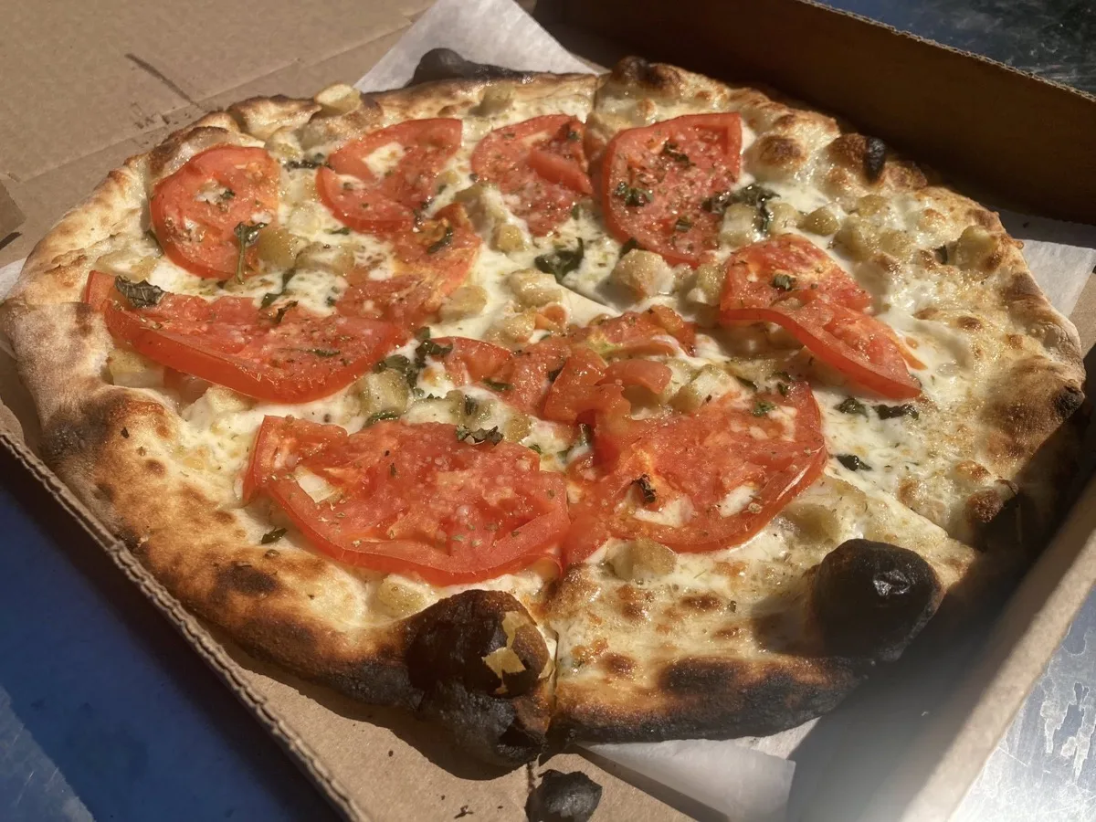 Fresh margherita pie with sliced tomatoes from mobile pizza catering in Guilford CT