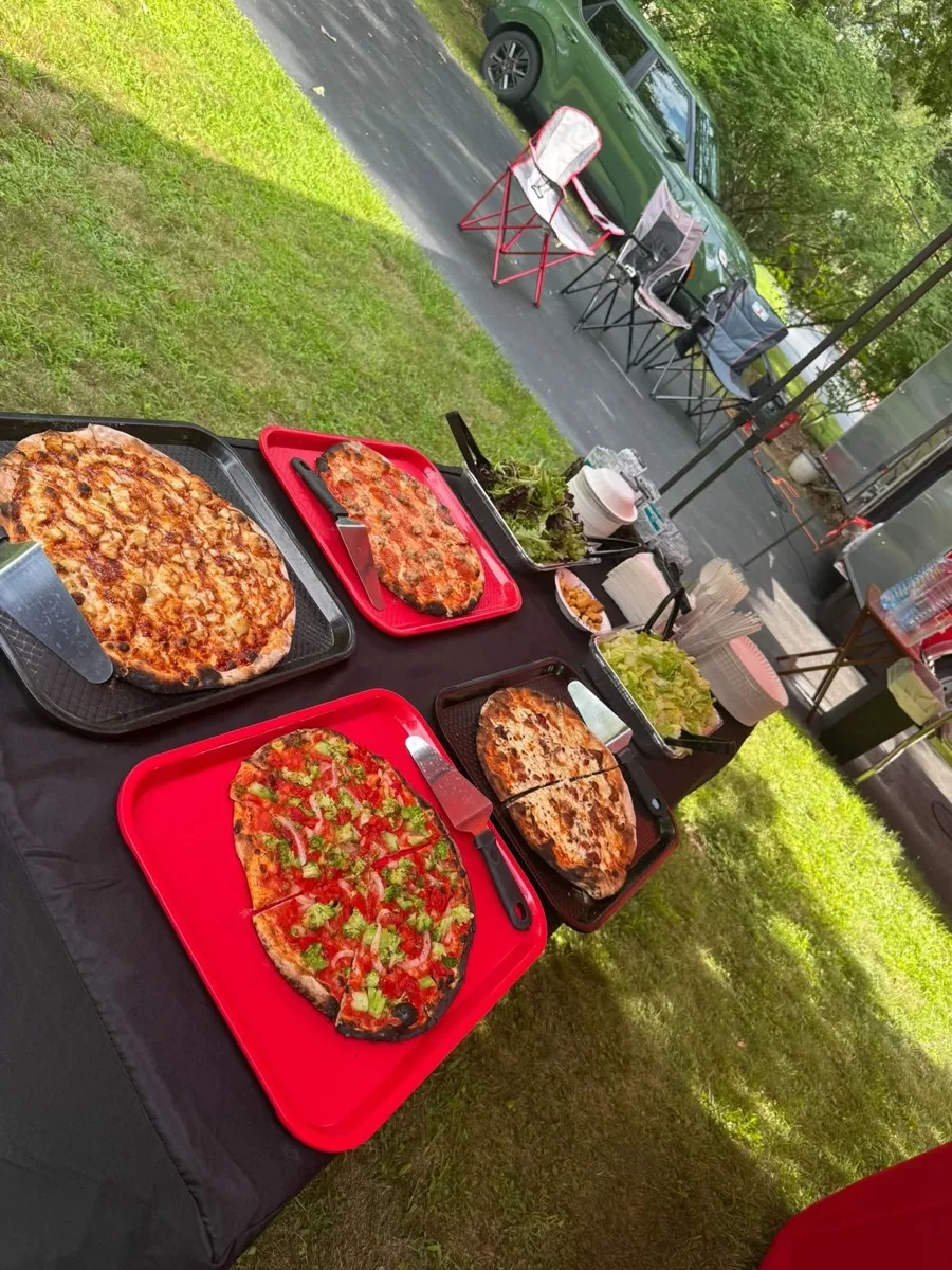 Spread of wood fired apizzas including veggie and chicken pies at an outdoor party in Connecticut