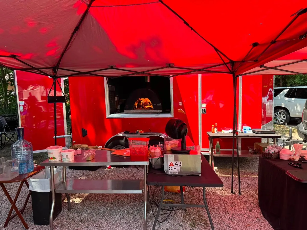 Wood fired oven burning inside the Rollin Dough pizza trailer at an evening catering event in Connecticut